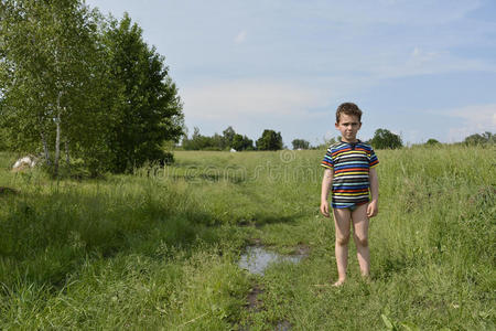 乡下男孩光着脚站在田里的路上.照片