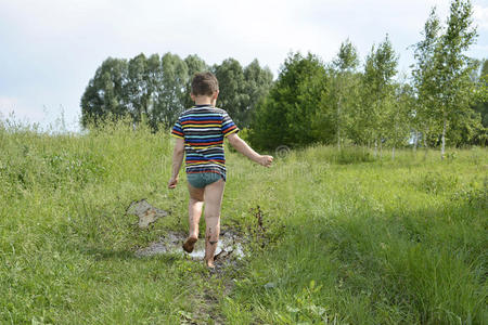 光着脚的男孩穿过水坑.照片