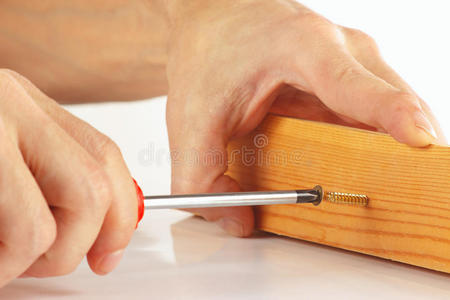 夜晚拧螺丝修理工手用螺丝刀将螺丝刀拧入木块照片