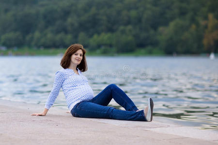 美丽的孕妇在河边放松