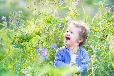 美丽的女婴在一个开着蓝色花朵的花园里
