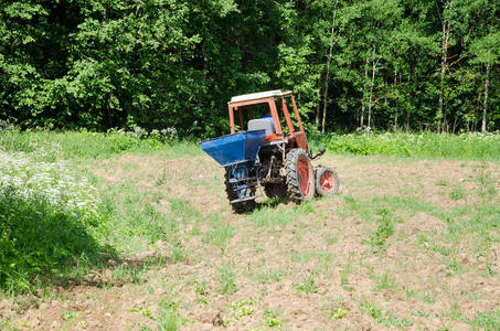 农民用拖拉机在地里播种荞麦种子