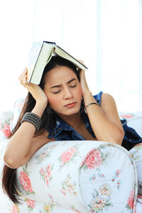 疲惫的年轻女子躺在沙发上看书在家小睡