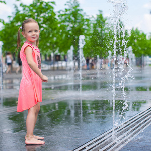 可爱的小女孩在街上的喷泉里玩得很开心