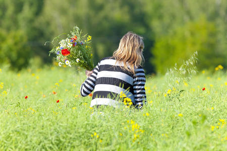 在草地上采摘野花的女人