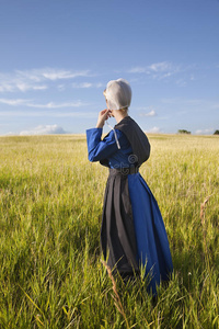 午后阳光普照的阿米什妇女站在草地上