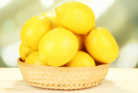 在明亮的背景上表格的柳条篮成熟柠檬