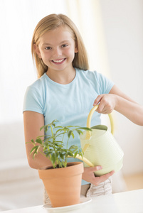 快乐的女孩浇水植物在家里