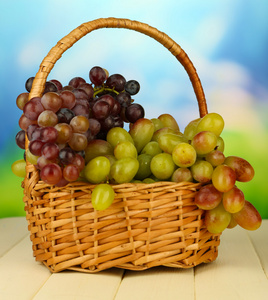 在明亮的背景上的柳条垫上的新鲜葡萄