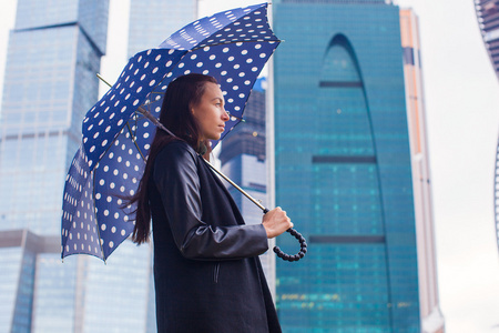 年轻迷人的商业妇女在伞下走在一个下雨天