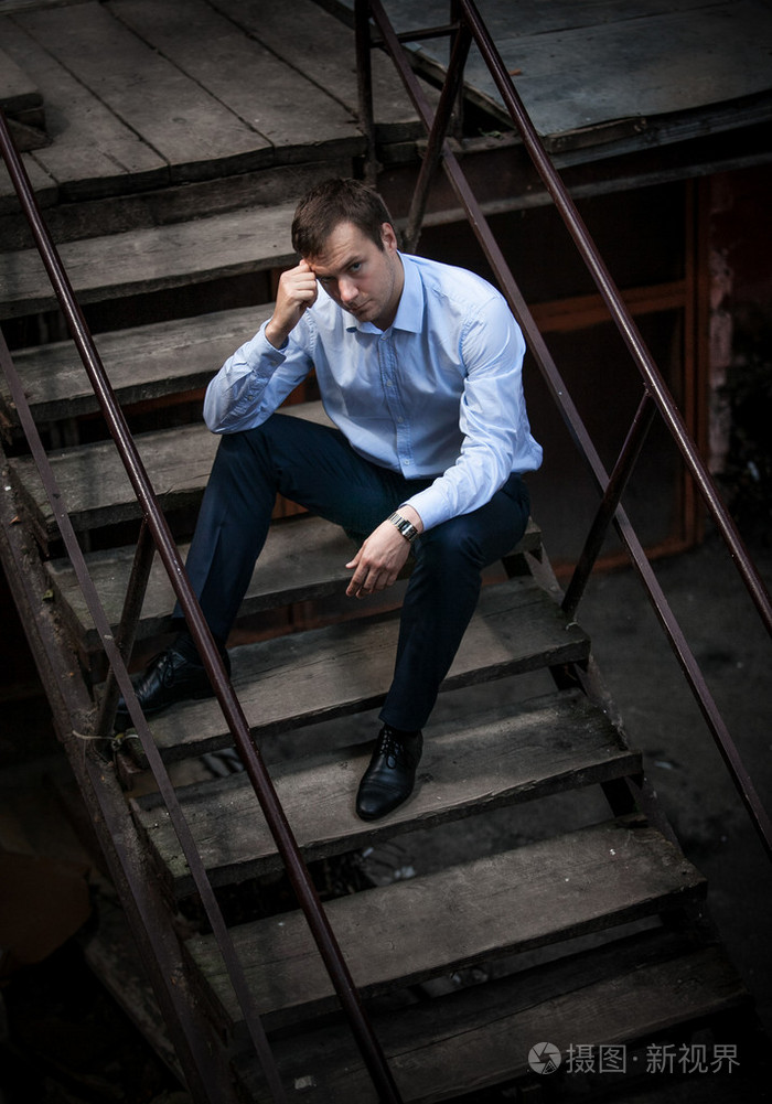 衬衫坐在楼梯上的男人