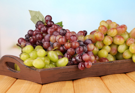 在明亮的背景上的木托盘上的新鲜葡萄