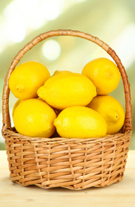 在明亮的背景上表格的柳条篮成熟柠檬