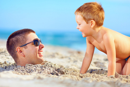父亲和儿子在沙上，很开心笑在海滩上