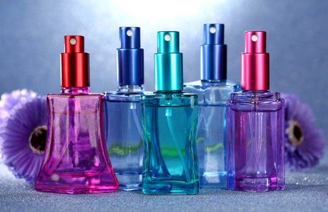 香水中美丽瓶子和鲜花在蓝色背景上的妇女