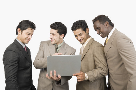 四个商人站着一台手提电脑
