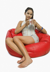 女人坐在一杯咖啡的豆袋