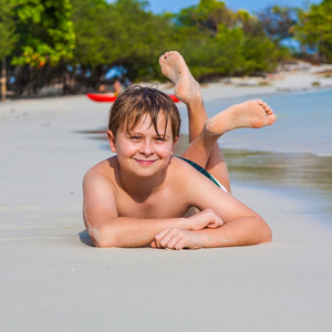 男孩是躺在沙滩上和享受水的暖意和寻找自我自信和快乐