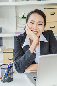 商业妇女快乐与手提电脑在办公室