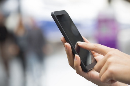 手女人用她的手机在一个火车站的特写照片