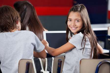 女学生在教室里的桌子举行数字平板电脑