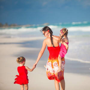 母亲和两个可爱的女儿走在异国风情的沙滩上阳光灿烂的日子