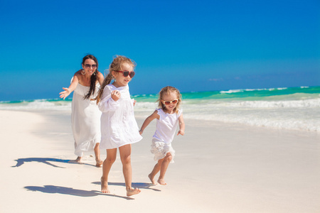 年轻快乐的妈妈和她可爱的女儿，在异国风情的沙滩上阳光明媚的日子开心