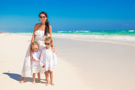 年轻的母亲和两个她可爱的孩子们在异国风情的沙滩上阳光灿烂的日子