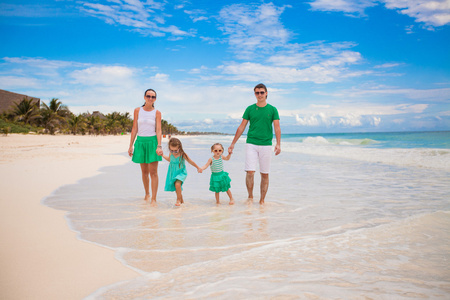 年轻漂亮的四人家庭享有在海滩上放松