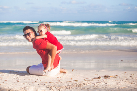 年轻的父亲和他可爱的小女儿在海滩得开心