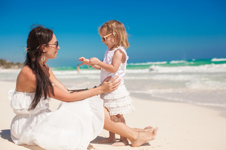 可爱的小女儿，她年轻的妈妈玩在墨西哥坎昆，白色的沙滩上