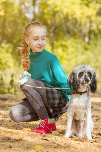 可爱的女孩，带着狗在秋天的公园里散步