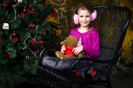 小女孩坐在附近一棵圣诞树