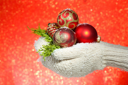 女手连指手套在彩色背景上的圣诞树球