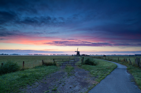 日出时的草地上的荷兰风车