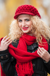 年轻漂亮的女人，在秋季时装拍摄。美丽时尚的年轻女孩与顶红色的帽子和红色的围巾，在公园里。与构成室外的红色配饰的金发女人。漂亮的金