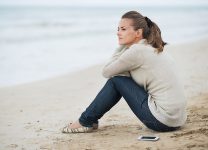 在寂寞的海滩上的毛衣的女人图片