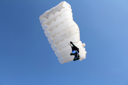 跳伞运动员和白色降落伞在蔚蓝的天空