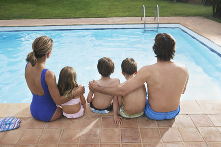 坐在游泳池旁的家庭