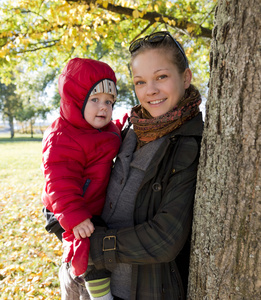 年轻的母亲和她蹒跚学步的儿子在片秋色的公园