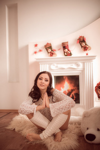 年轻漂亮的女孩坐在旁边的壁炉和圣诞树