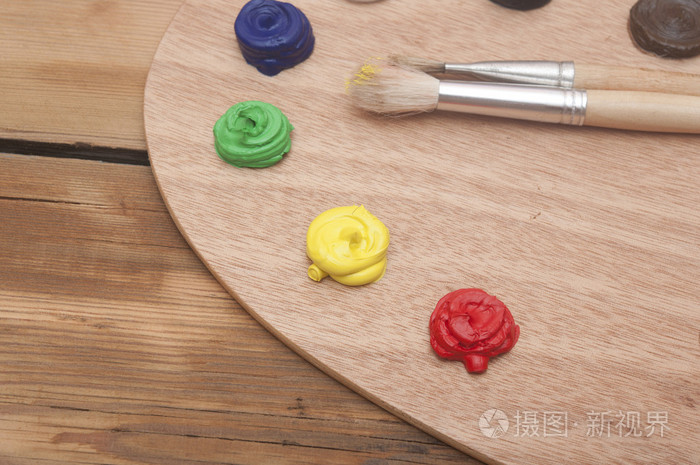 油画颜料和油漆刷坐在木质的黑色的调色板上