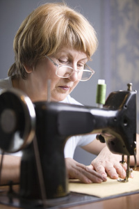 成熟的女人在缝纫机工作