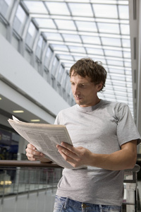 年轻男子站在读报纸图片