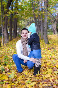 年轻的父亲和他可爱的小女儿在秋天公园低语