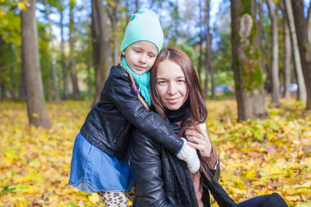 幸福的母亲和她可爱的女儿，温暖的阳光明媚的日子，在黄色的秋天的树林开心
