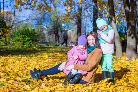 年轻的母亲带着她美妙的美丽女儿在片秋色的公园，在一个温暖的晴天