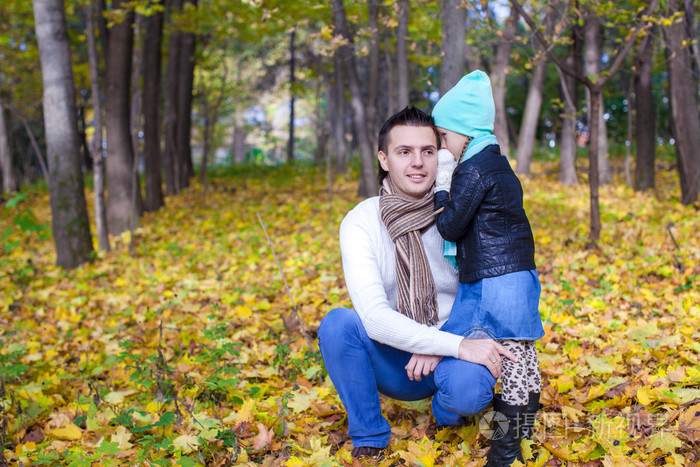 年轻的父亲和他可爱的小女儿在秋天公园低语