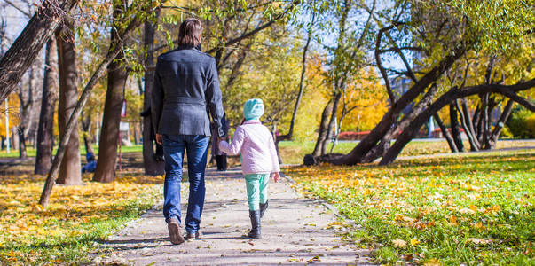 后方的看法，年轻的父亲和小女孩走在秋天的公园