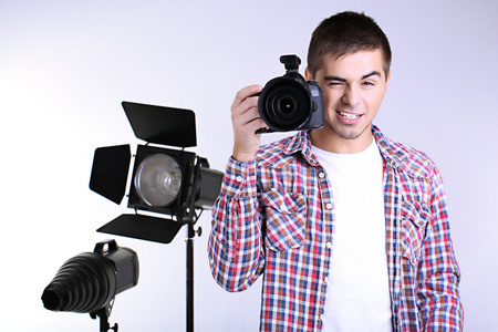 英俊的摄影师用相机照片工作室背景